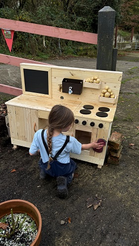 Young girl playing with a mud kitchen