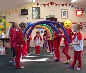 group of young children making an archway with pool noodles