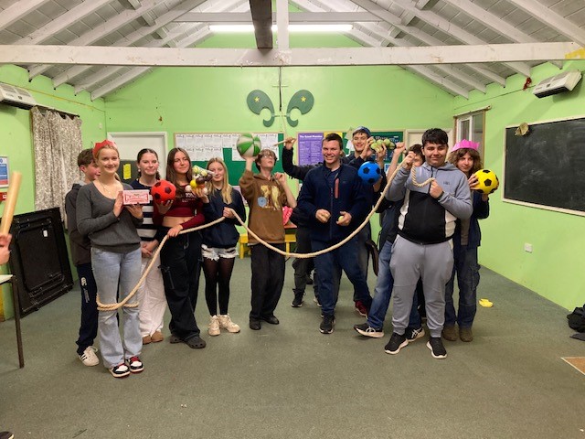 Teenagers holding varioous sports equipment and toys