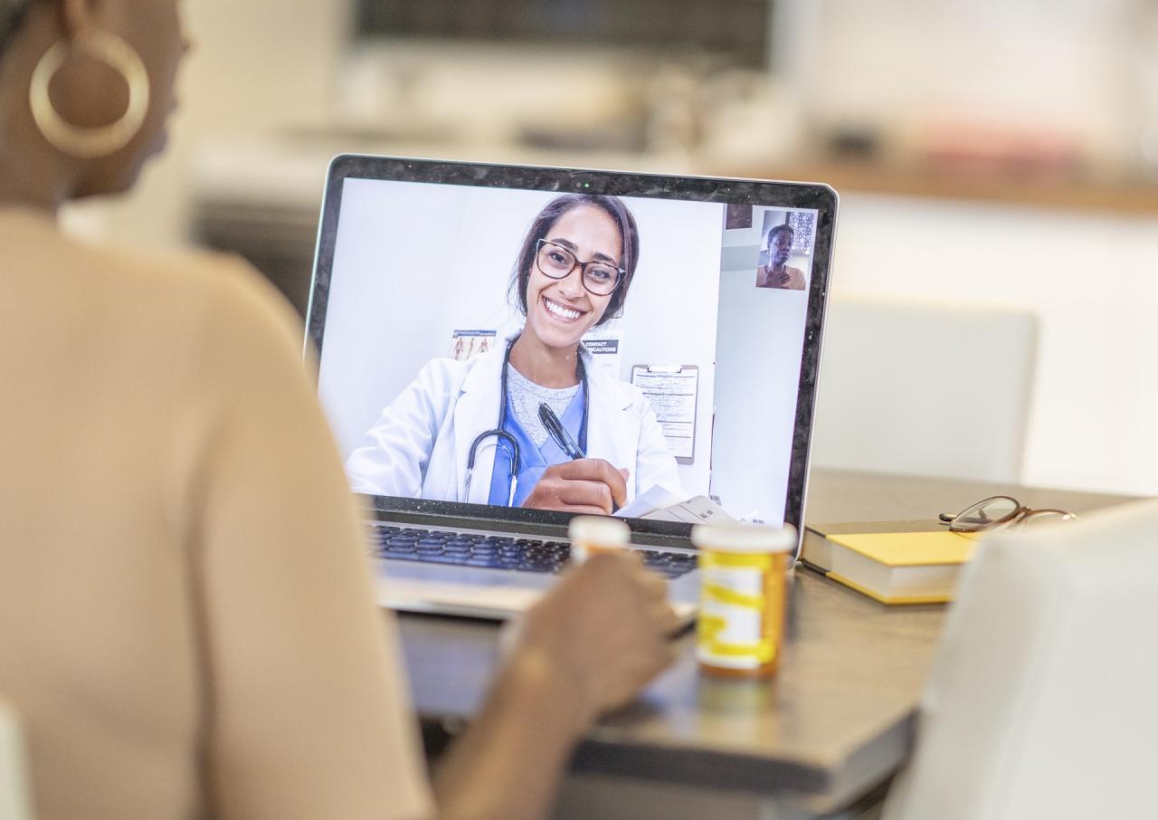 Online medical consultation with a female doctor in a white lab coat showing on a laptop screen. 