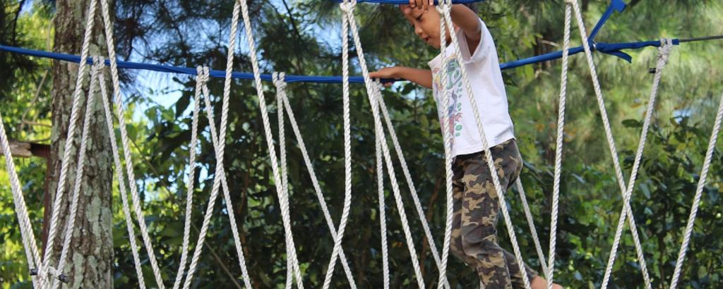 young boy walking across a rope bridge