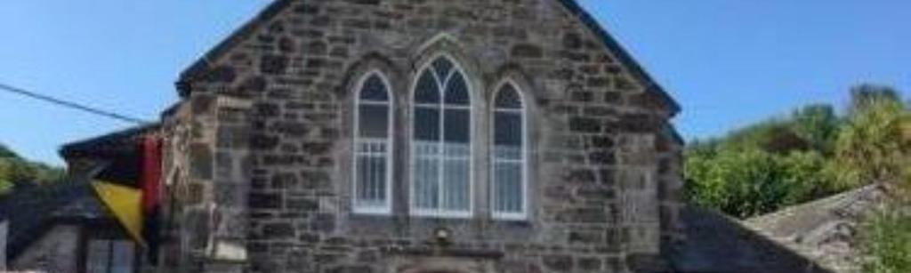 A photograph of the Village Hall showing the clock and bell