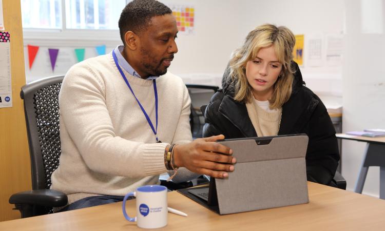 Male adviser helping young female at a laptop