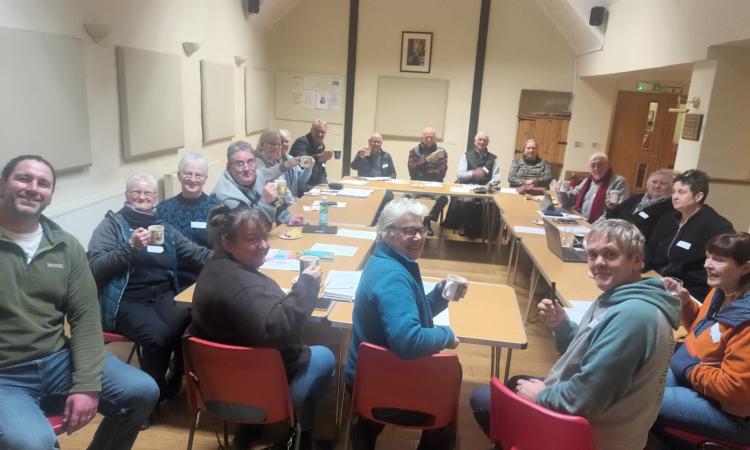 Group of smiling people sitting in a village hall 