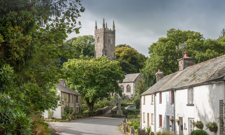 Village scene with a church and white house and green trees