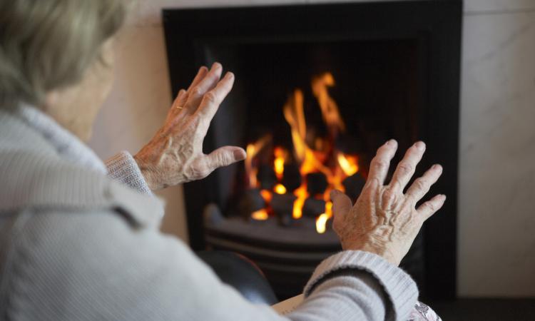 elderly lady warming hands by fire