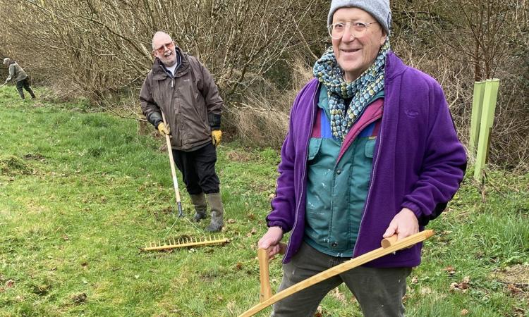 person standing in a field holding a scythe
