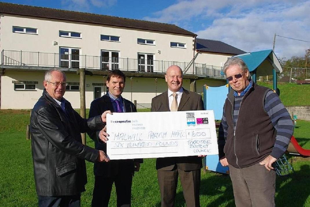 The photo shows Barry Parsons presenting a cheque for £600 towards new recycling bins that will be situated in the Parish hall car park.