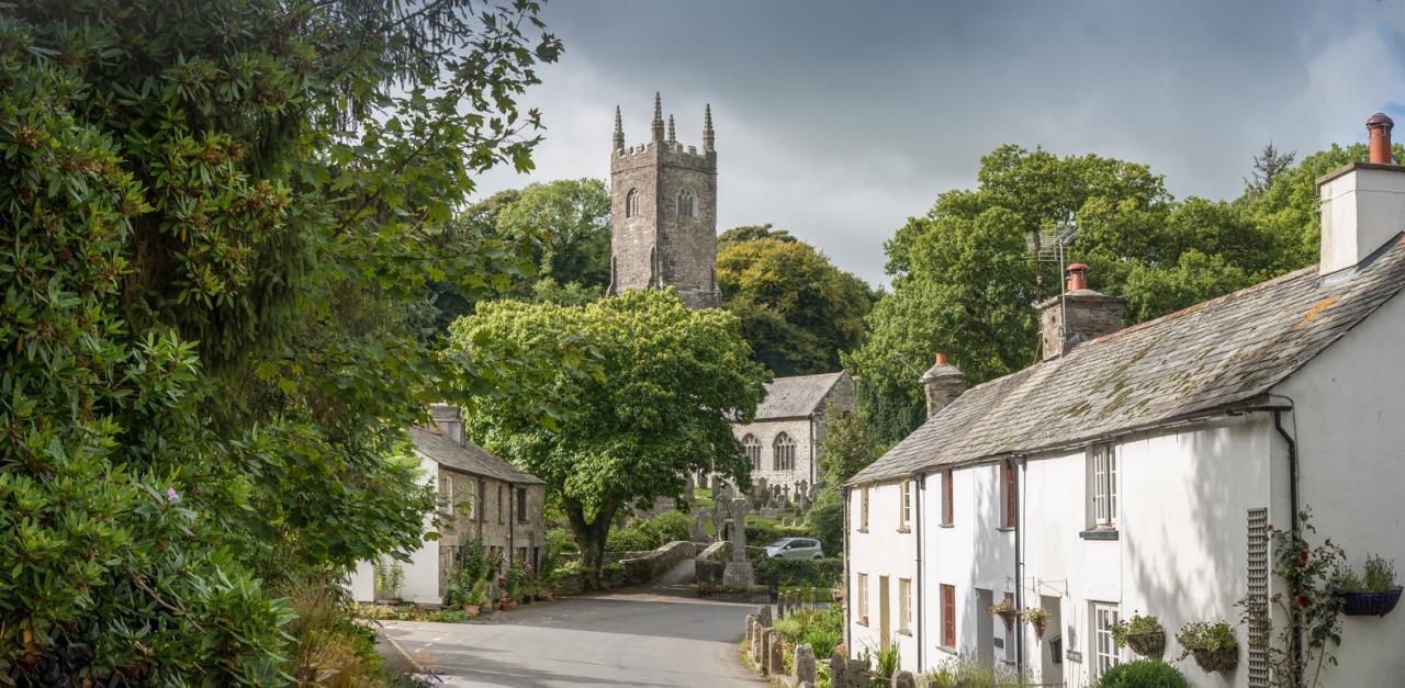 Village scene with a church and white house and green trees