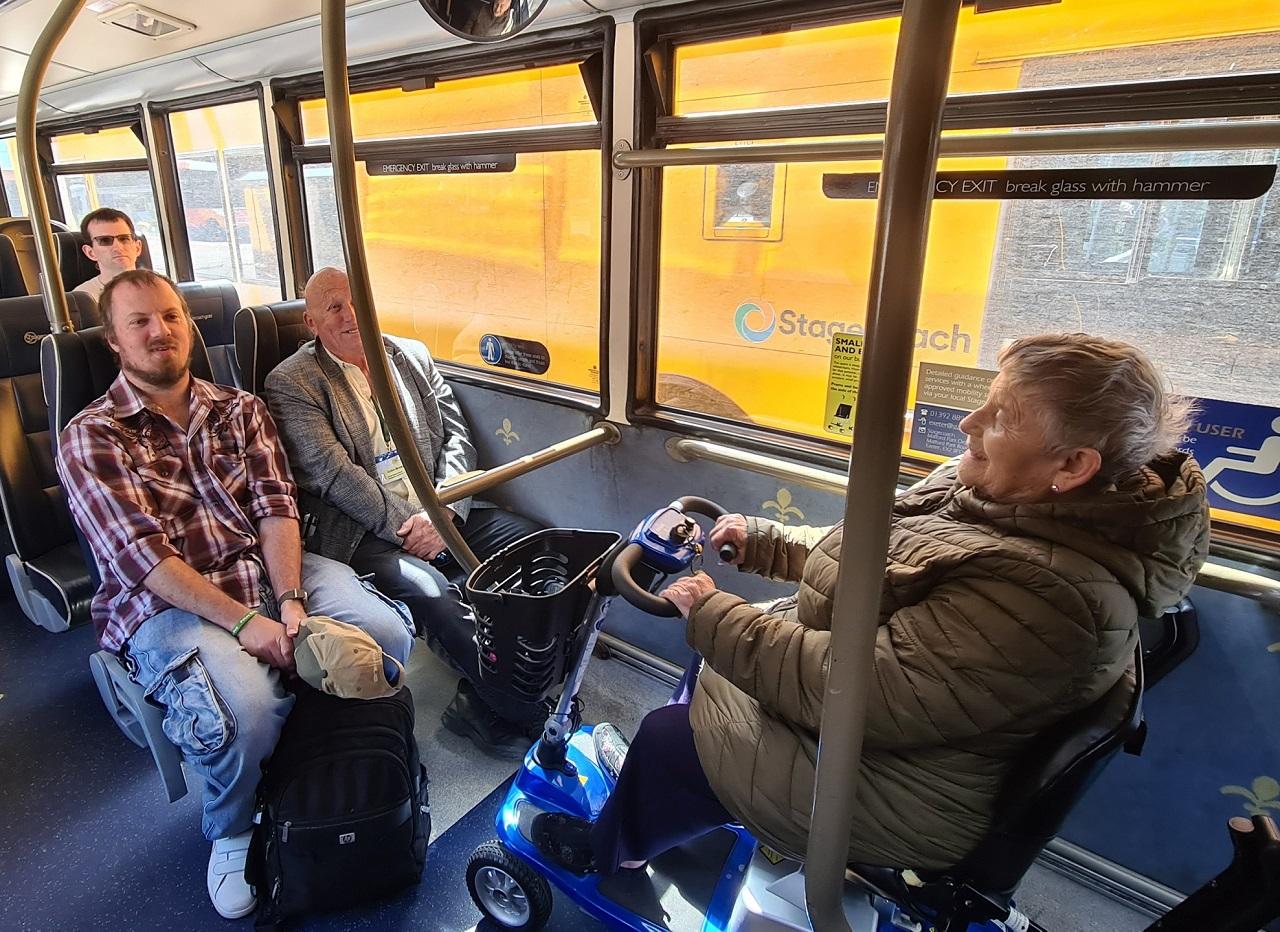 People on a  bus including a woman in a motorised chair