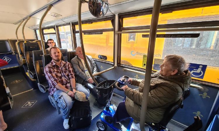 People on a bus, including a woman in a mobility scotter